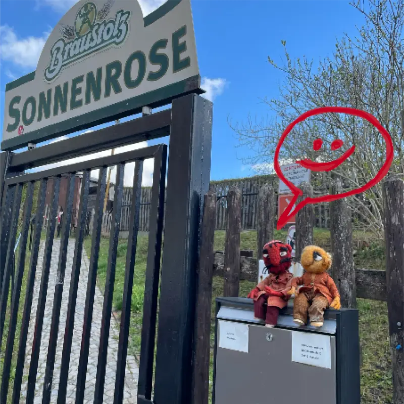 Zwei Puppen auf einem Briefkasten am Eingang der Sonnenrose, mit einem Smiley in der Sprechblase